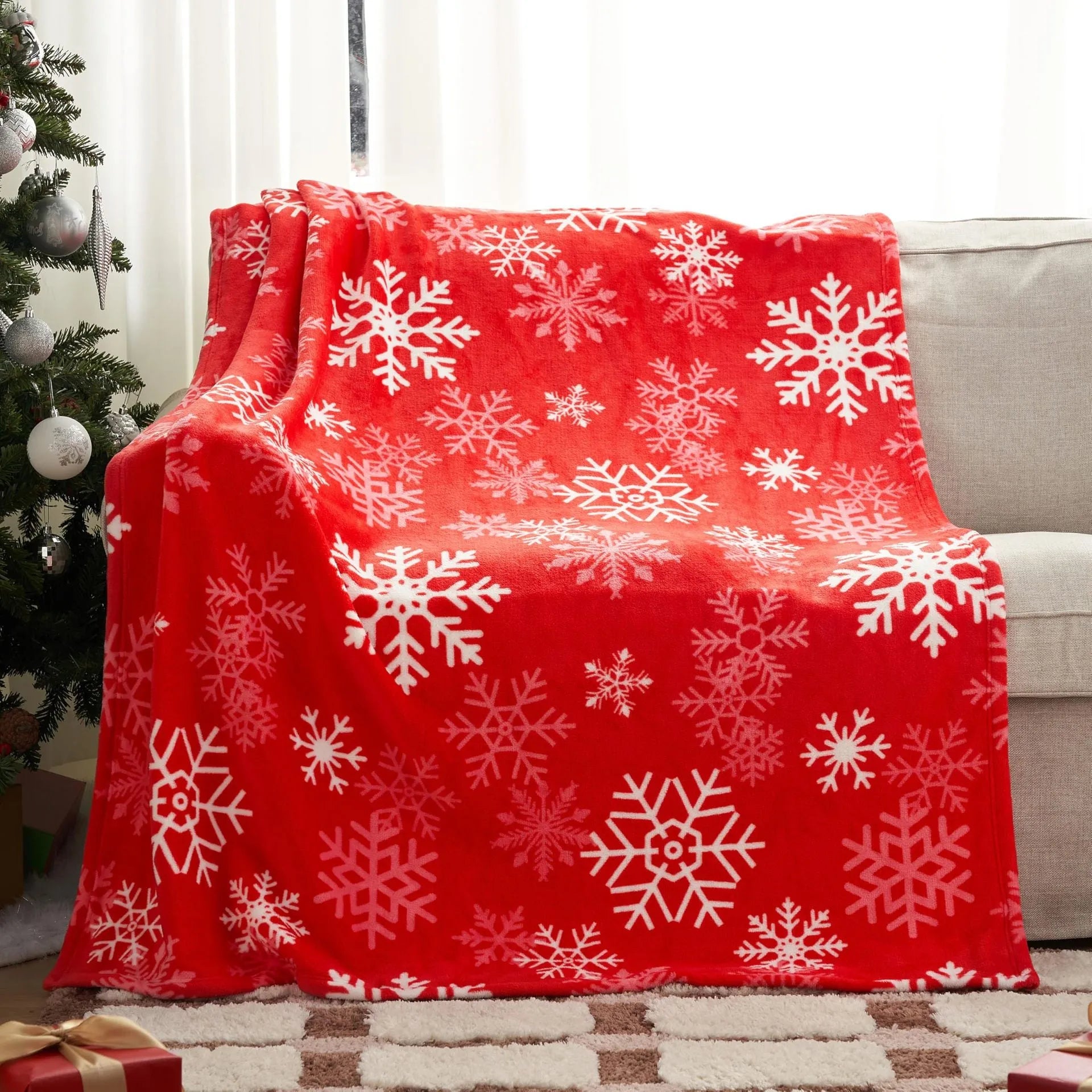 Soft red flannel Christmas blanket draped over a bed corner