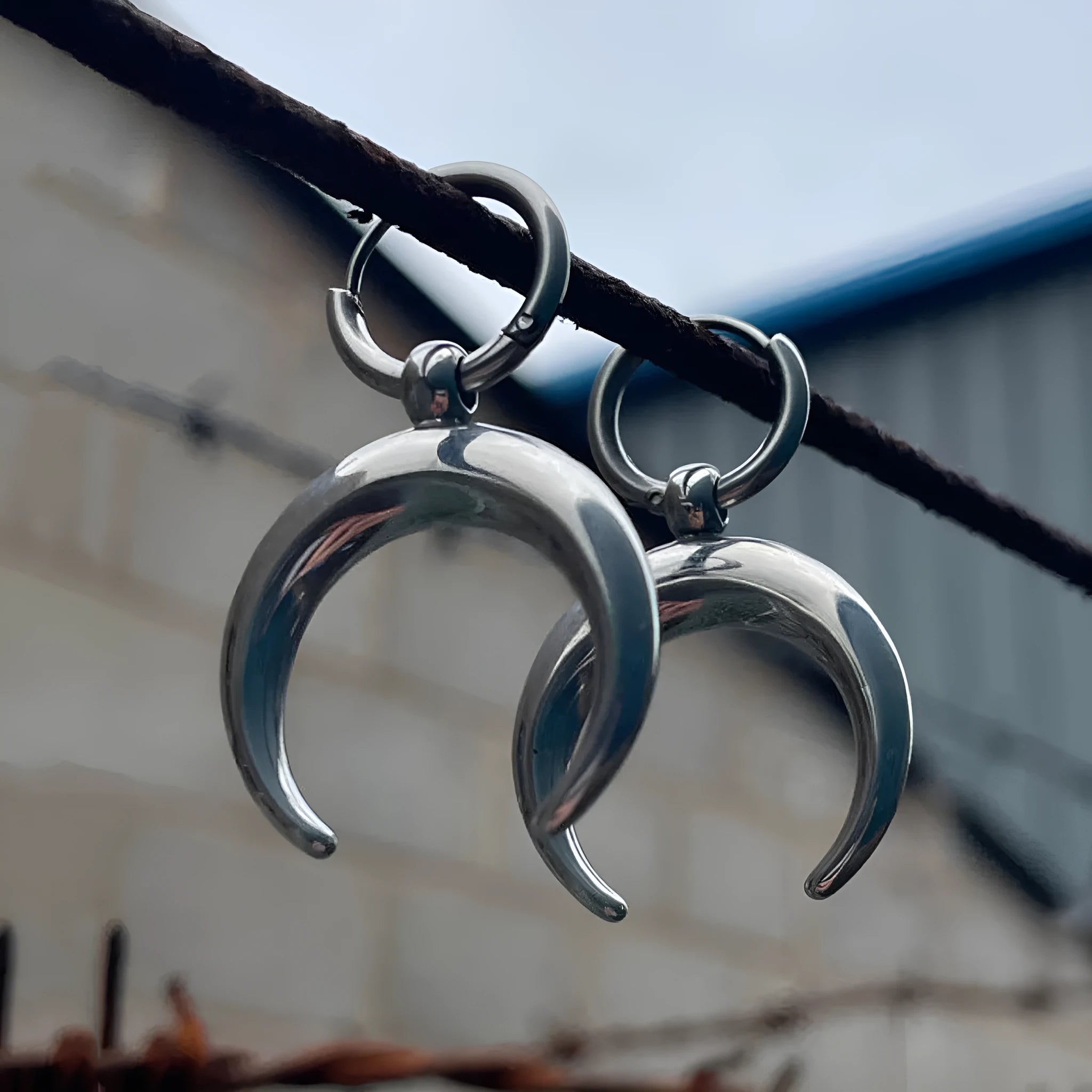 Silver-colour large hoop earrings with moon detailing and geometric shape on ear clip fastening