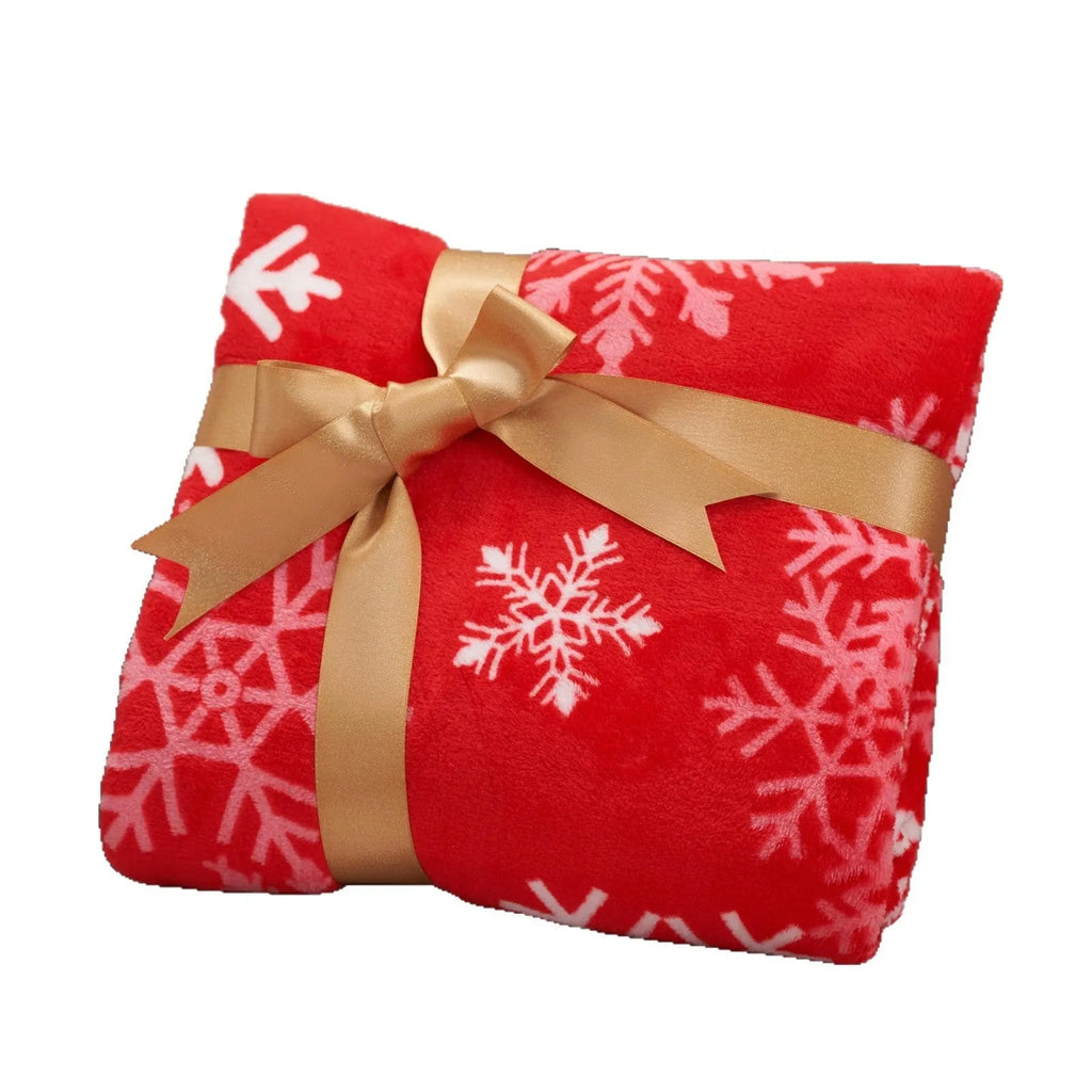 Soft red flannel Christmas blanket draped over a bed corner