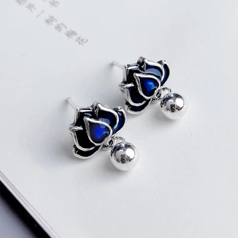 Blue lotus flower ear studs with seedpod tassel detail on an alloy backing.