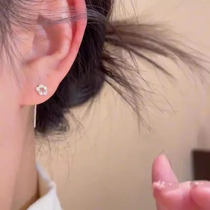 Pair of silver colour hollow flower stud earrings with detailed petal elements and needle posts