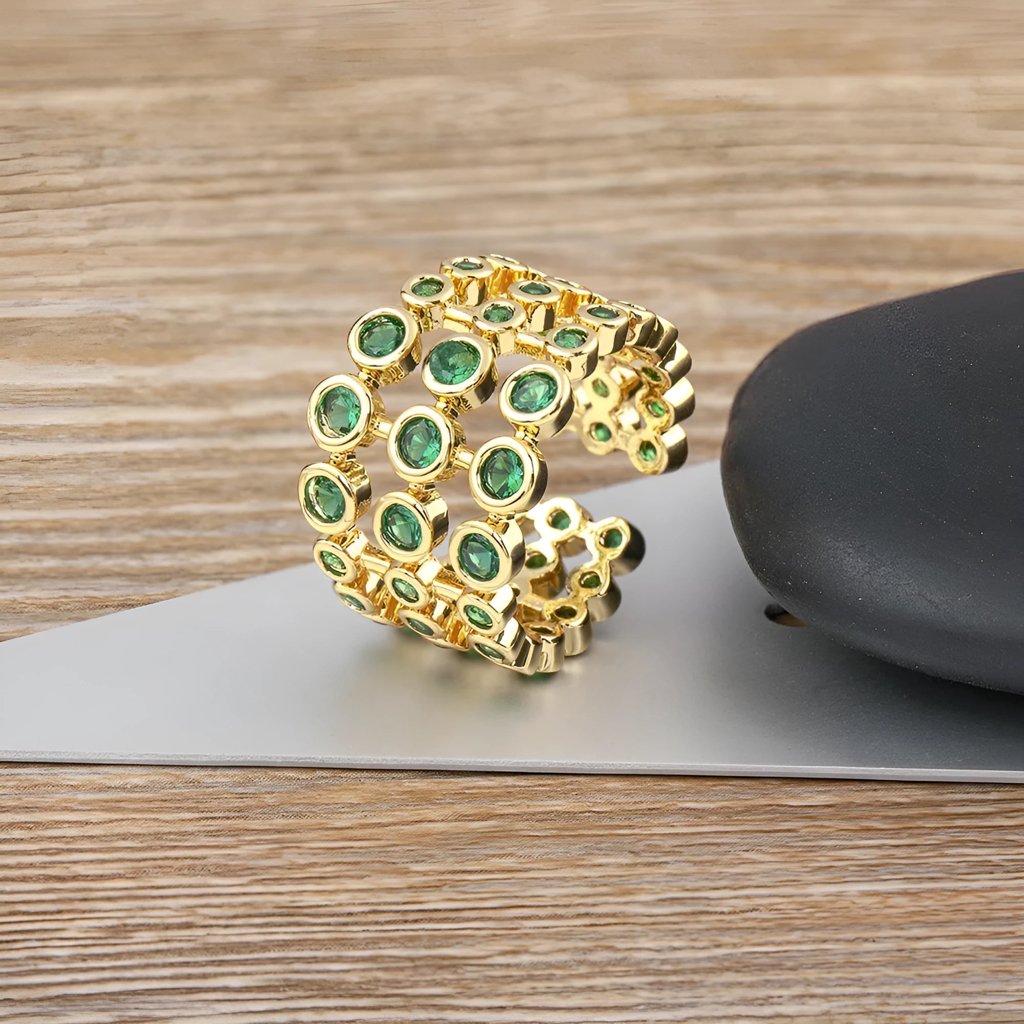 Copper ring with 18K gold plating showing three-layer exaggerated design and green zirconia stones