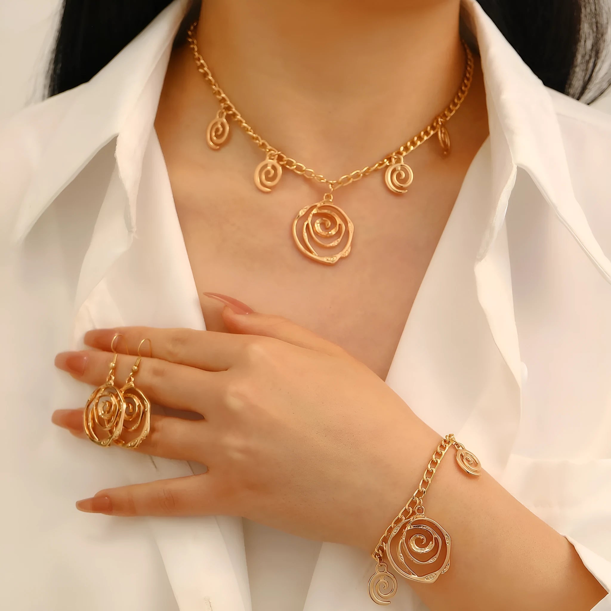 Gold spiral donut design necklace, bracelet, and earrings set on a grey background.