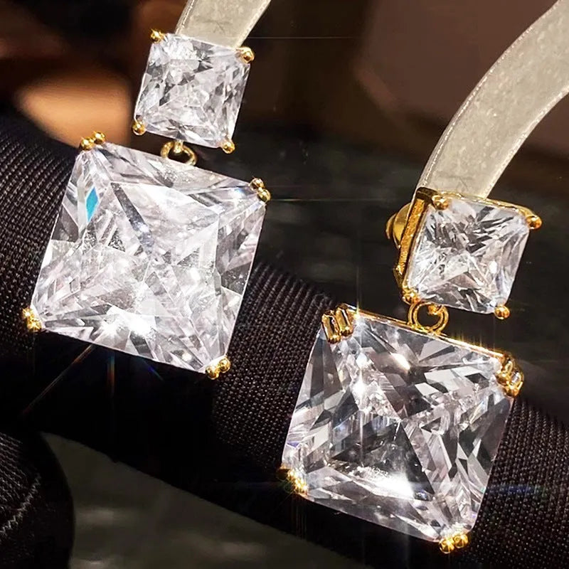 A pair of geometric square copper earrings with a quadrilateral design, shown in white gold and gold colour options.