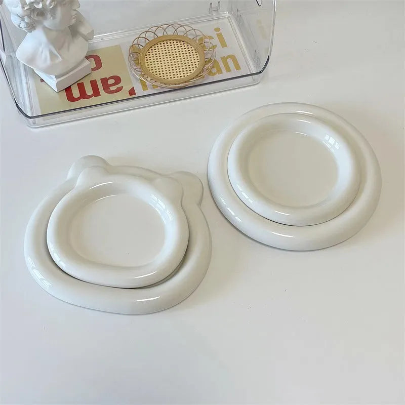 White round ceramic plate with bear doodle design, used as a saucer for a small succulent plant pot.