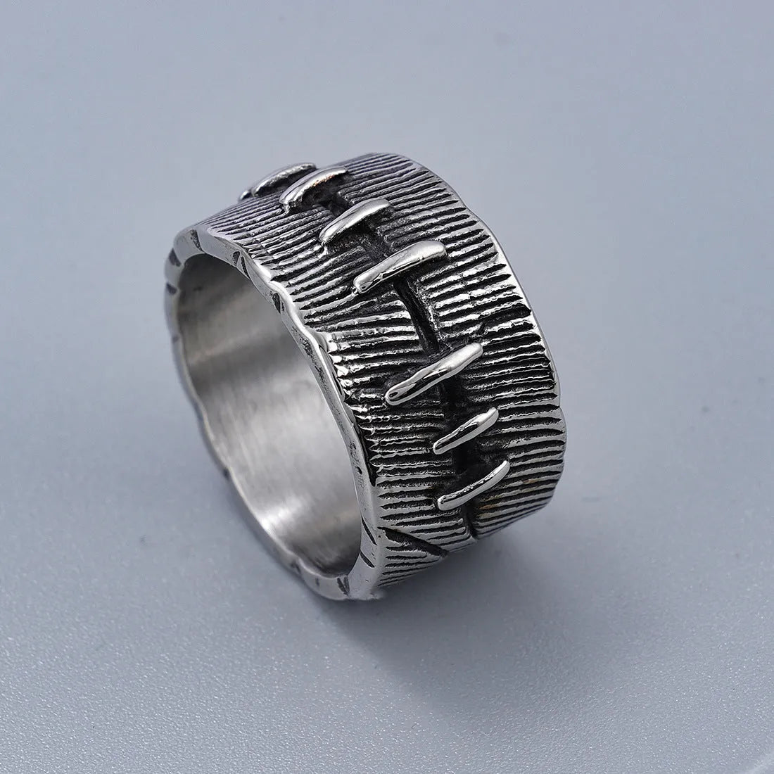 Geometric dark punk titanium steel double ring in retro colour, showing stitched design on a hand.