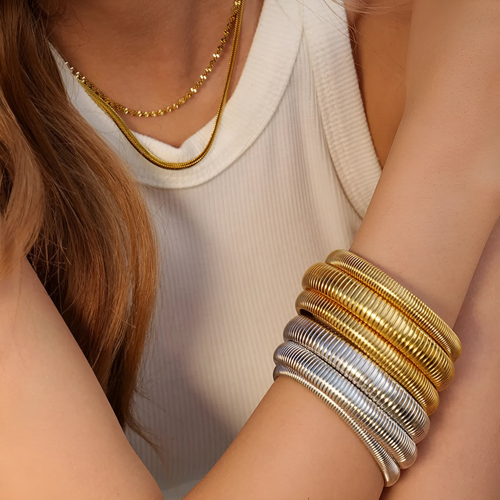 Women's titanium steel bracelet with elastic rings and vertical stripe pattern in gold or silver.