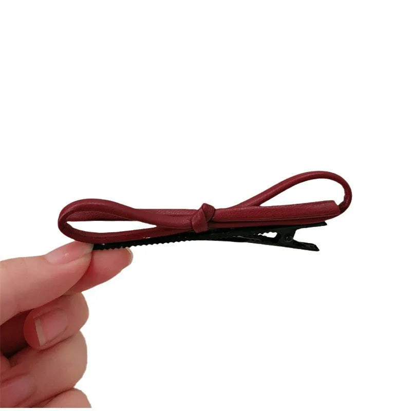 Close-up of a wine red leather bow barrette hair clip on dark hair.