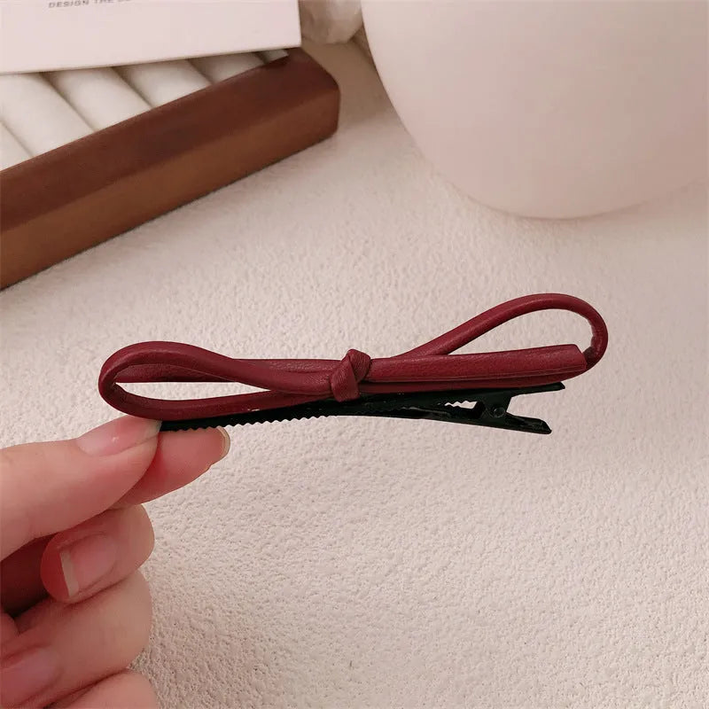 Close-up of a wine red leather bow barrette hair clip on dark hair.