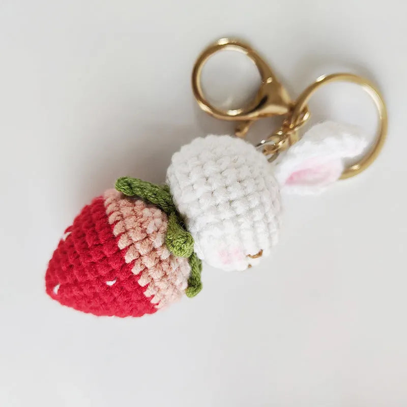 Hand-woven white wire rabbit strawberry pendant on a key.