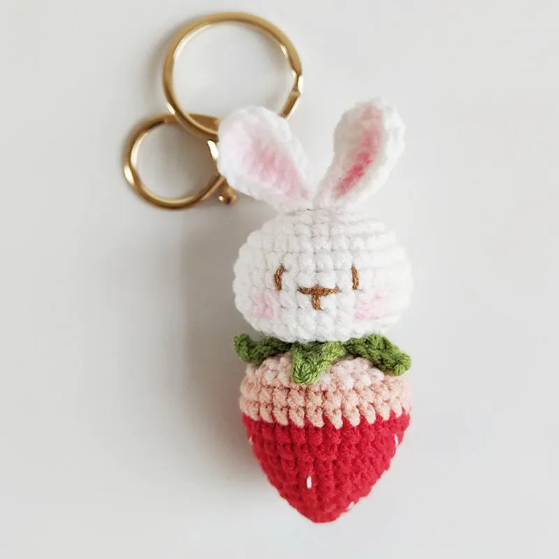 Hand-woven white wire rabbit strawberry pendant on a key.