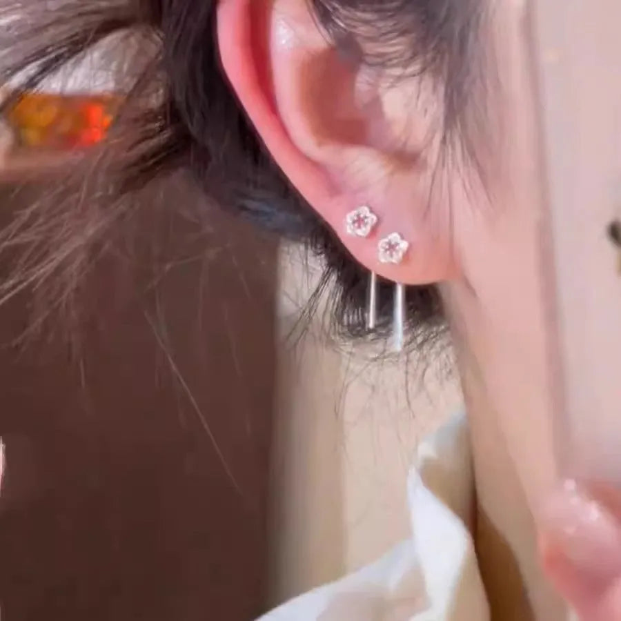 Pair of silver colour hollow flower stud earrings with detailed petal elements and needle posts