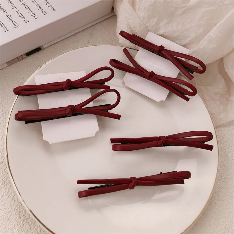 Close-up of a wine red leather bow barrette hair clip on dark hair.