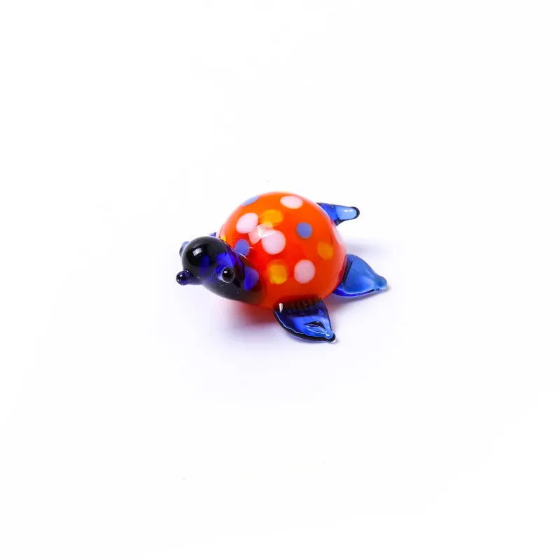 Geometric glass turtle ornament in a modern style with a coloured shell, displayed on a desktop.