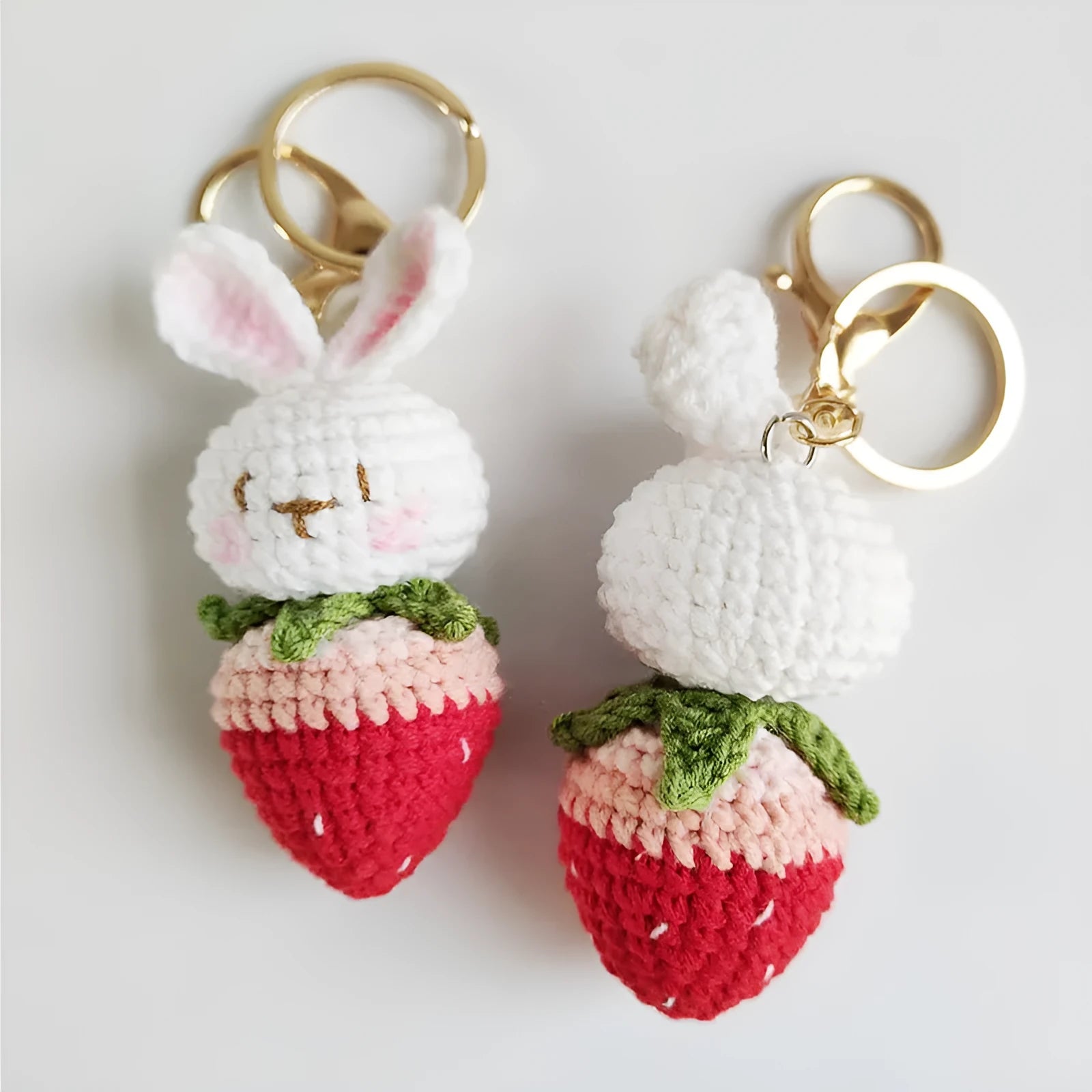 Hand-woven white wire rabbit strawberry pendant on a key.