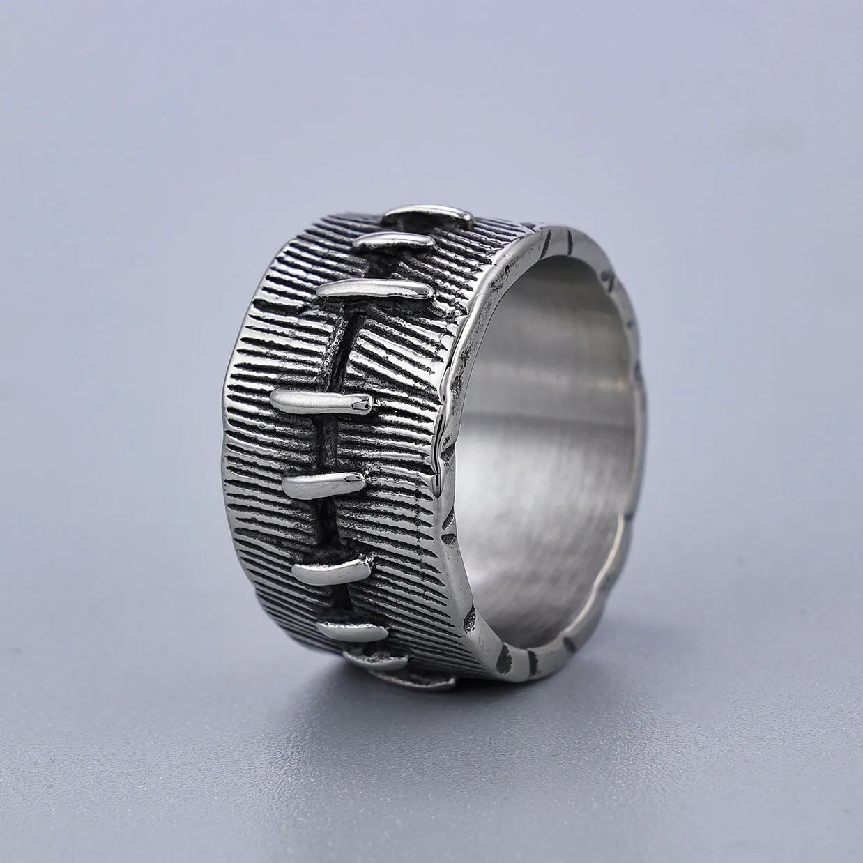 Geometric dark punk titanium steel double ring in retro colour, showing stitched design on a hand.