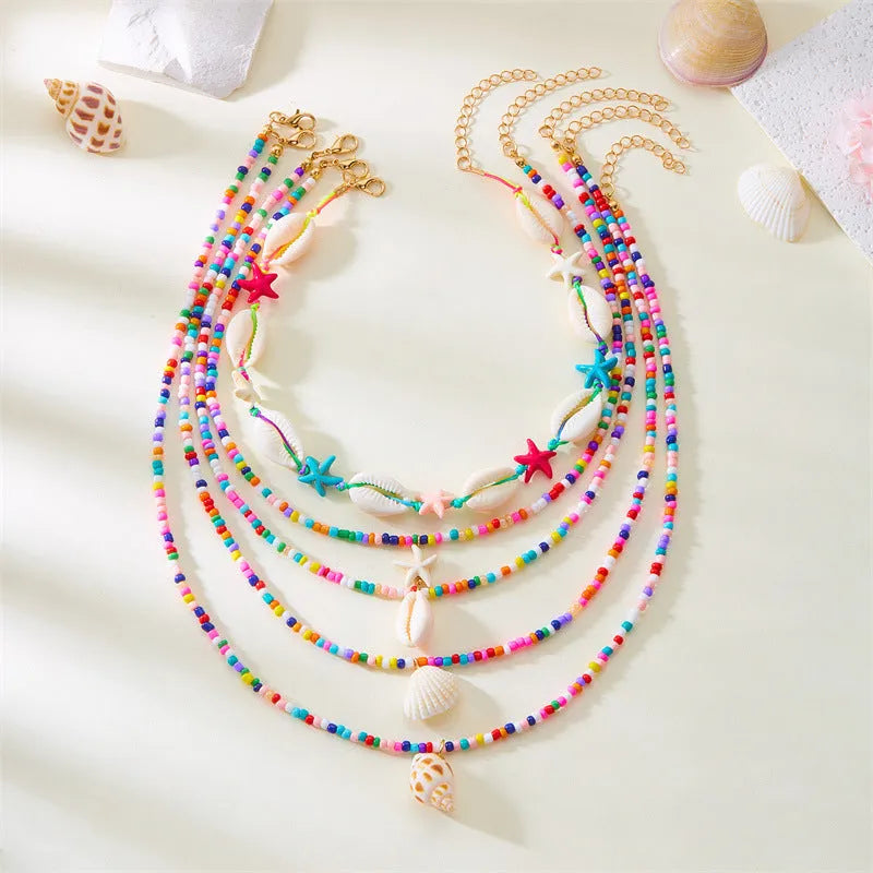 Women's multi-layer necklace set with blue shell pendants and beads, showing five coordinated designs