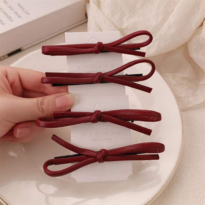 Close-up of a wine red leather bow barrette hair clip on dark hair.