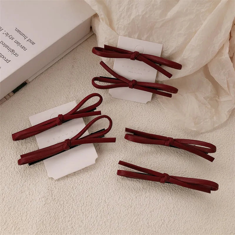 Close-up of a wine red leather bow barrette hair clip on dark hair.