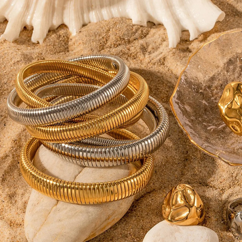 Women's titanium steel bracelet with elastic rings and vertical stripe pattern in gold or silver.