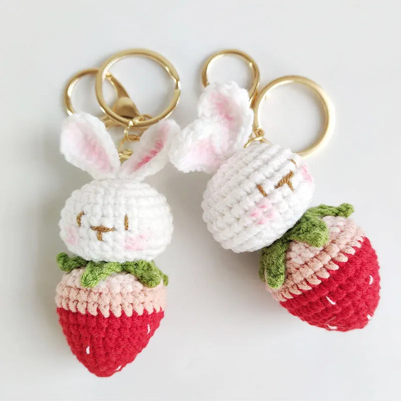 Hand-woven white wire rabbit strawberry pendant on a key.
