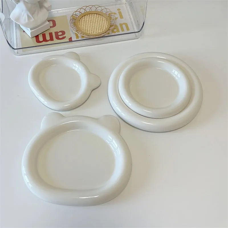 White round ceramic plate with bear doodle design, used as a saucer for a small succulent plant pot.