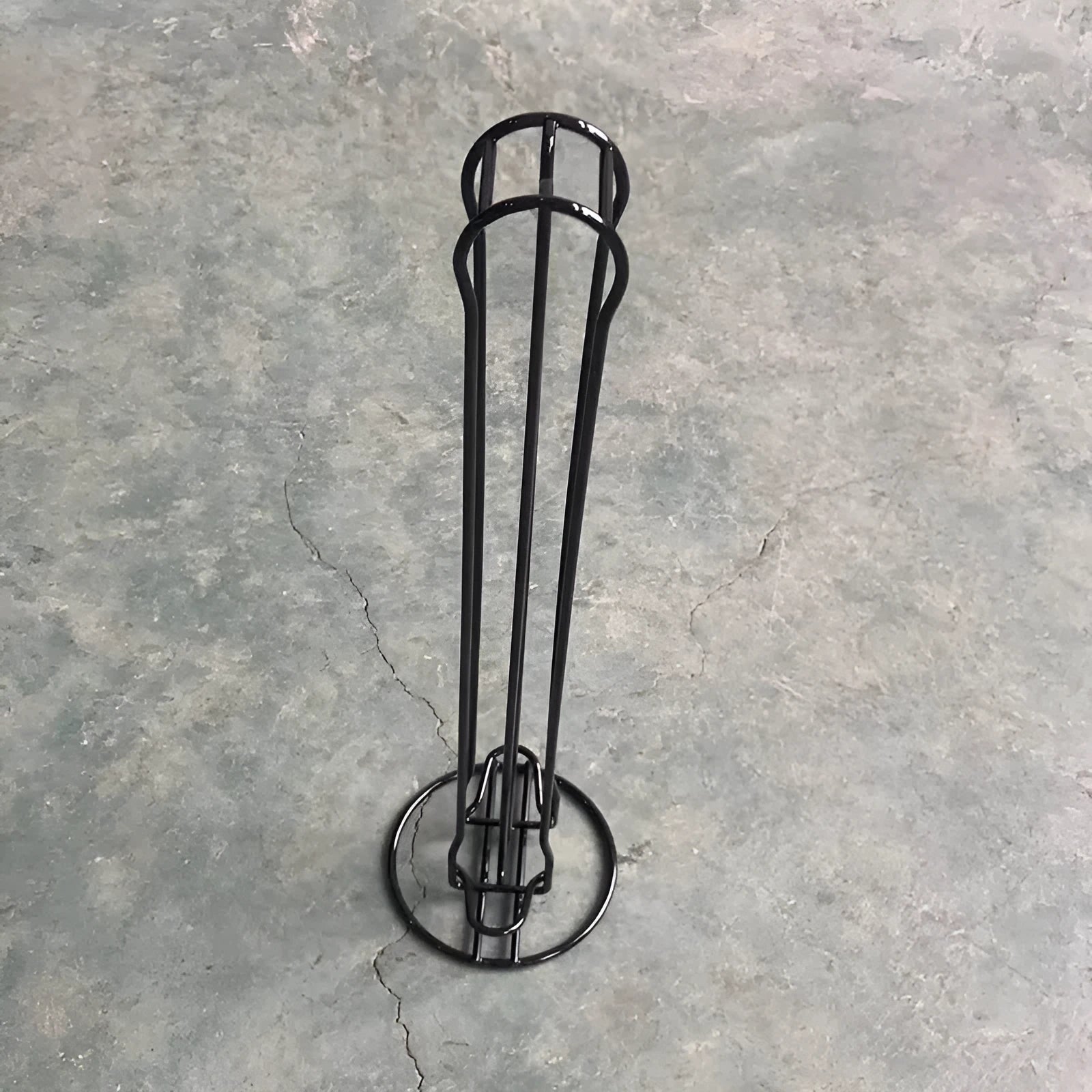 Black iron coffee capsule storage rack holding pods on display shelves.