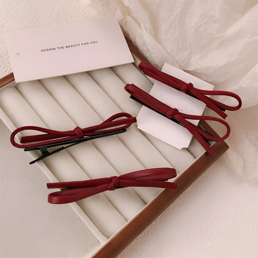 Close-up of a wine red leather bow barrette hair clip on dark hair.