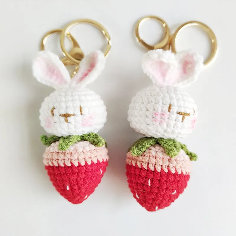 Hand-woven white wire rabbit strawberry pendant on a key.