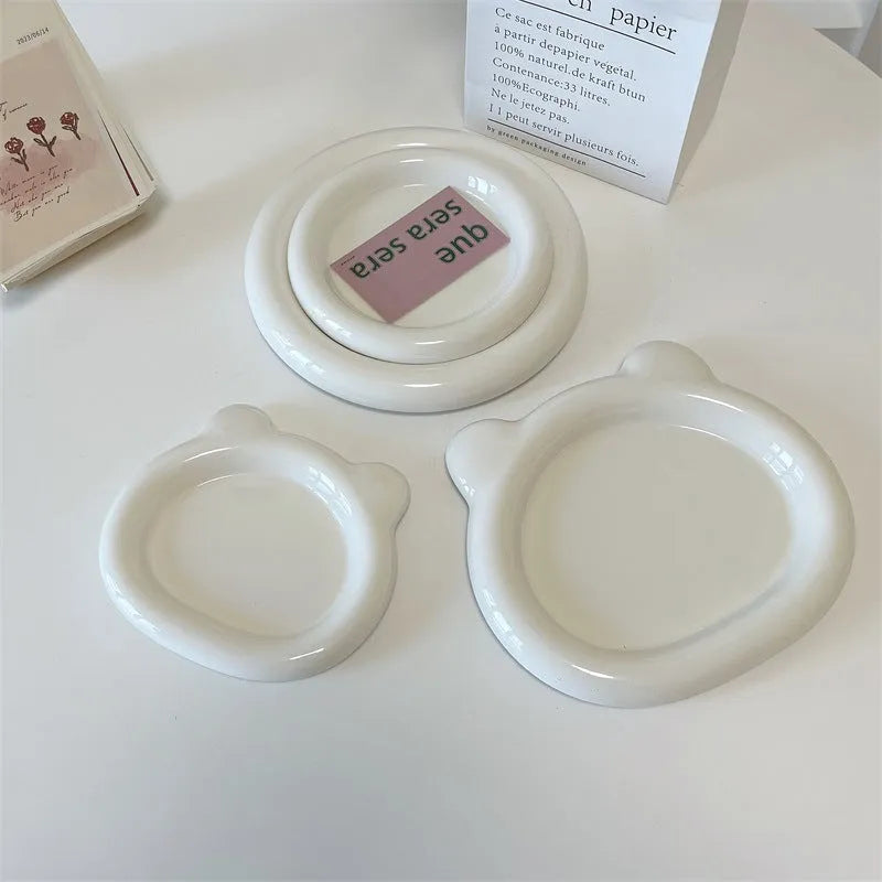 White round ceramic plate with bear doodle design, used as a saucer for a small succulent plant pot.