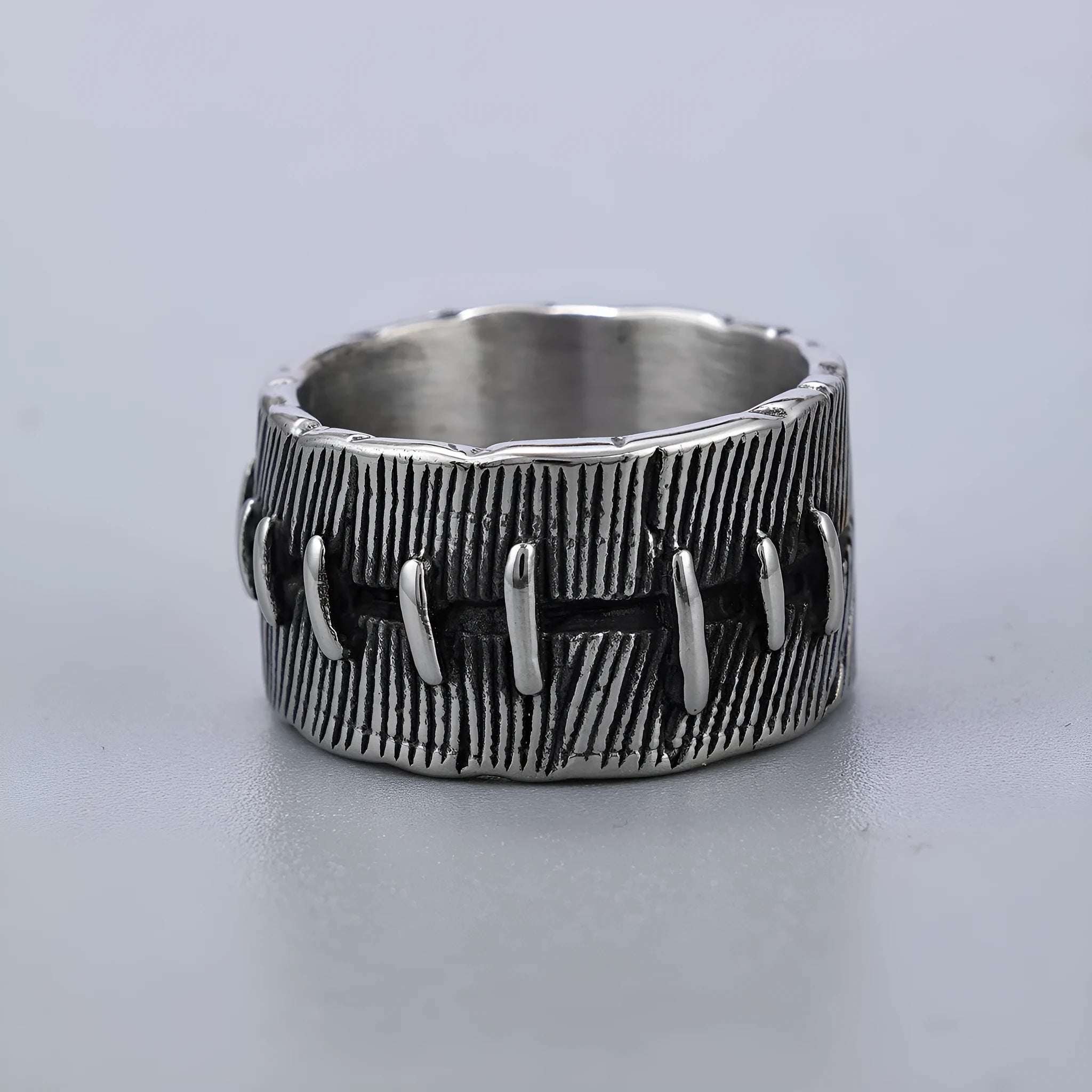 Geometric dark punk titanium steel double ring in retro colour, showing stitched design on a hand.