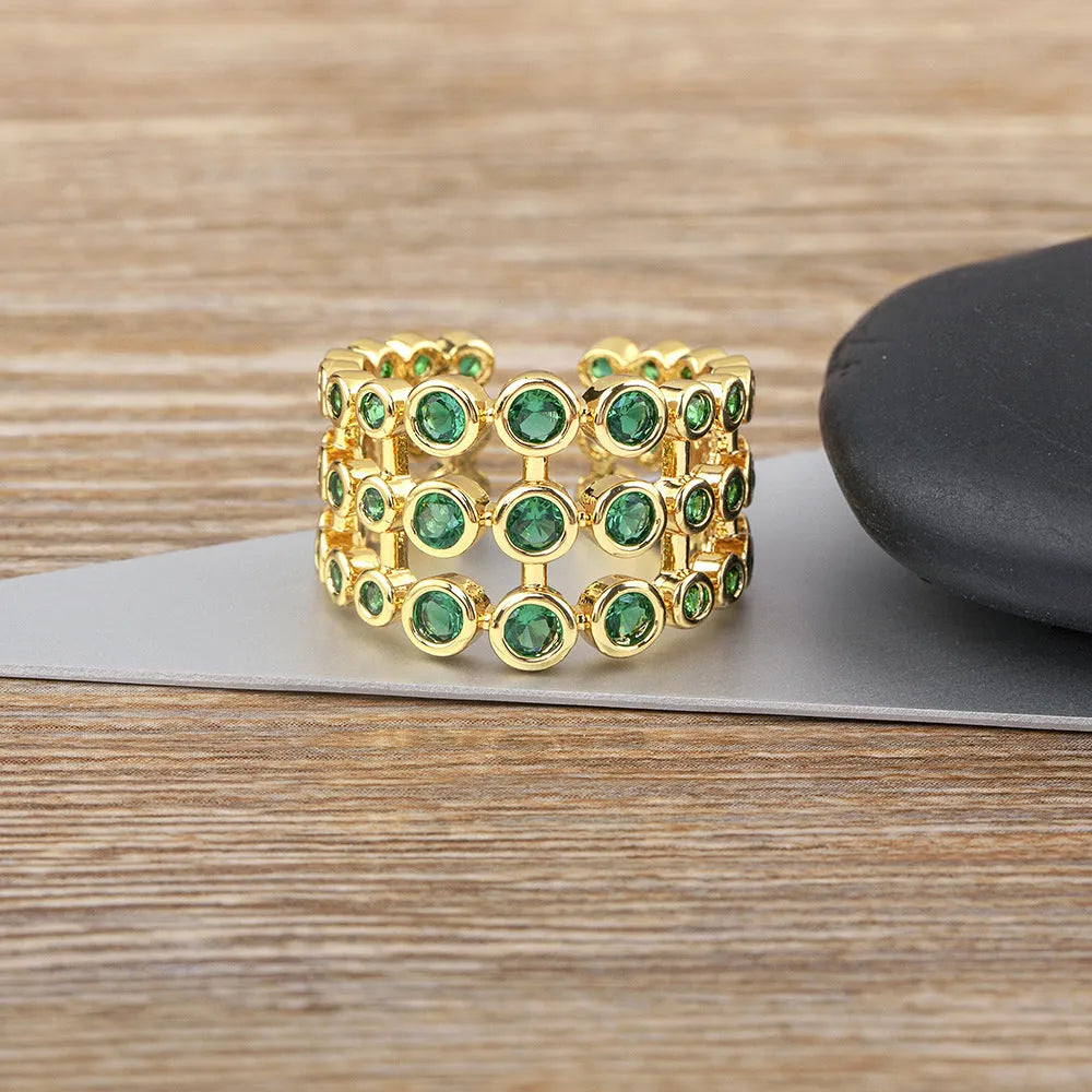 Copper ring with 18K gold plating showing three-layer exaggerated design and green zirconia stones