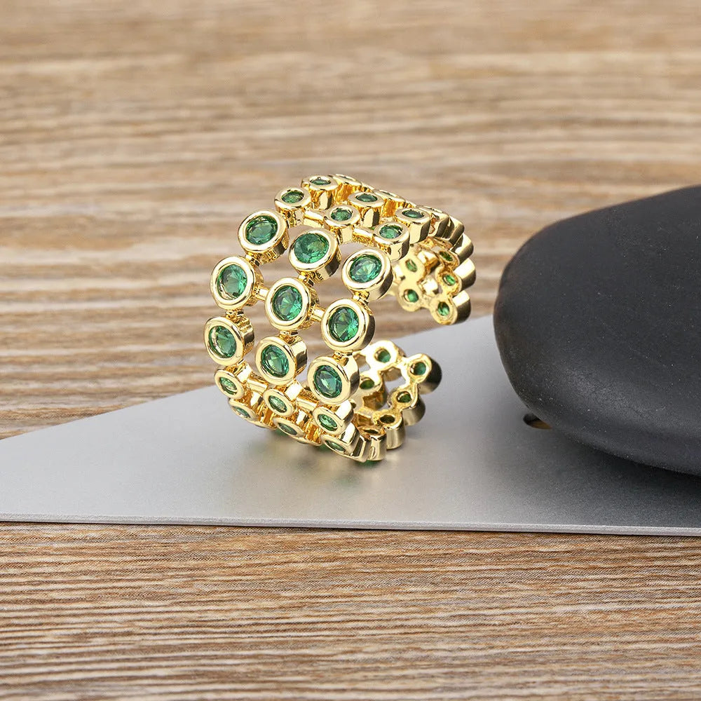 Copper ring with 18K gold plating showing three-layer exaggerated design and green zirconia stones