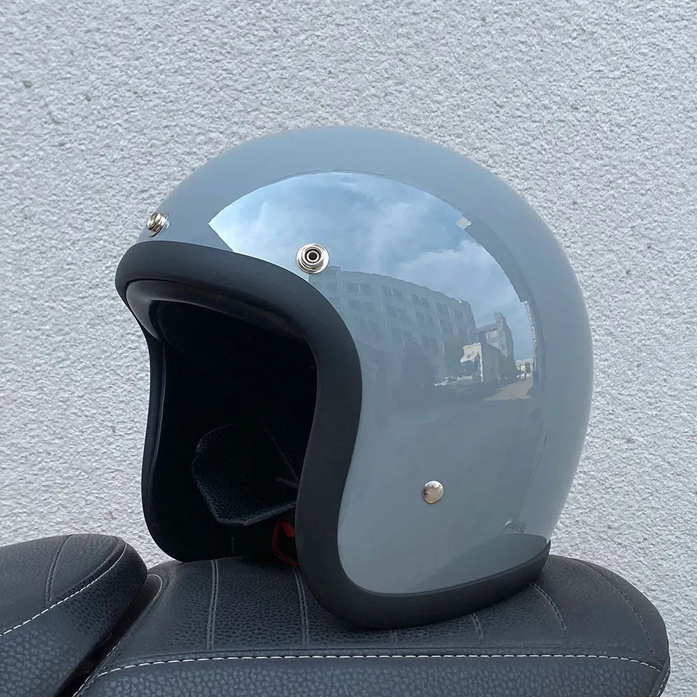 A cement grey retro-style motorcycle half helmet with a floral pattern on the side, showing its open-face design.
