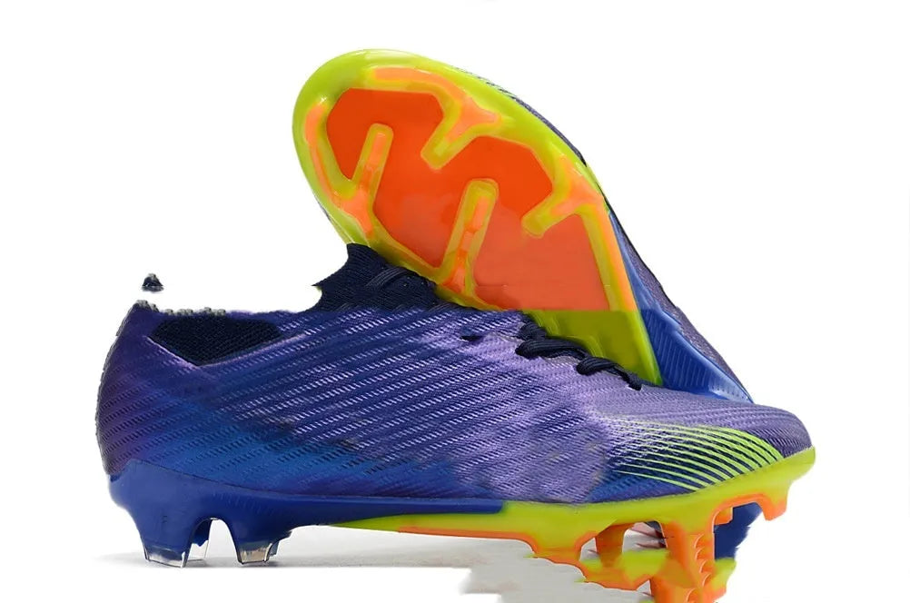 Men's low-top knitted football shoes with white/blue colourway, showing FG studs on rubber outsole and lace-up front.