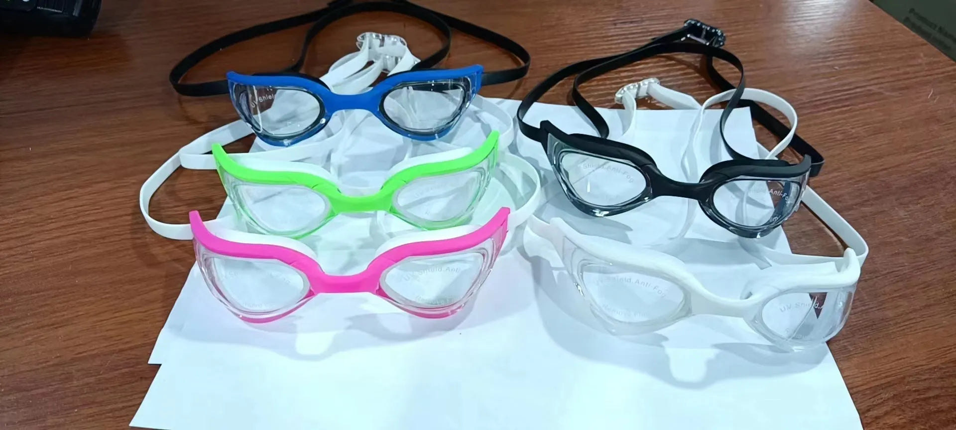 Racing style swimming goggles with mirror lenses and adjustable nose bridge on a blue background.