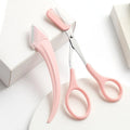 Close-up of a pink and white eyebrow trimming knife with a curved blade and a small comb on a white background.