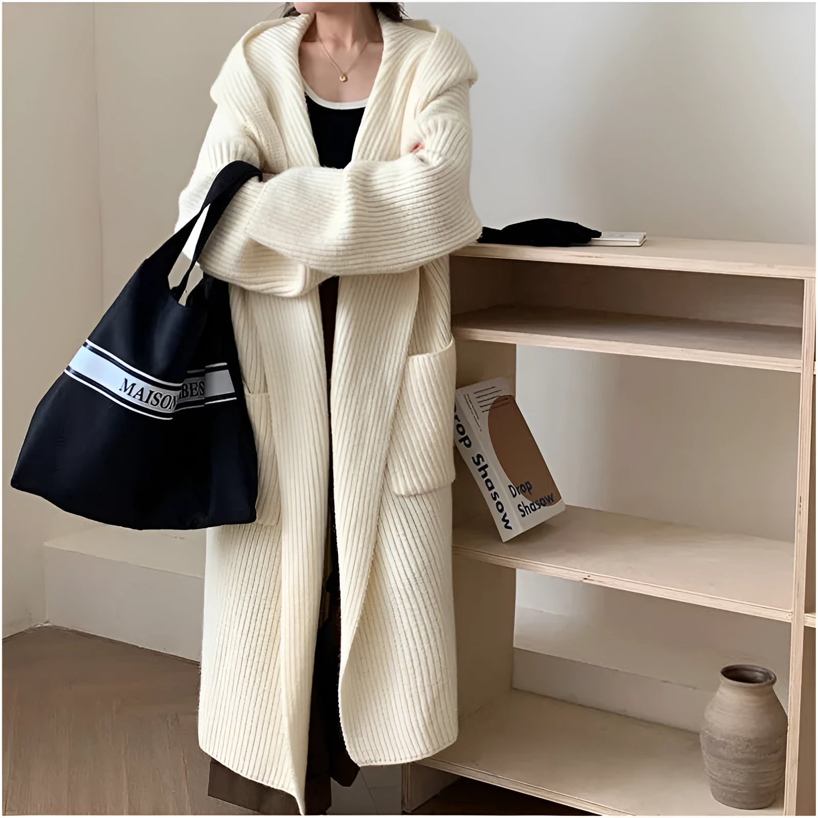 A long, loose grey hooded cardigan coat for women on a hanger, showing its length and raglan sleeves.