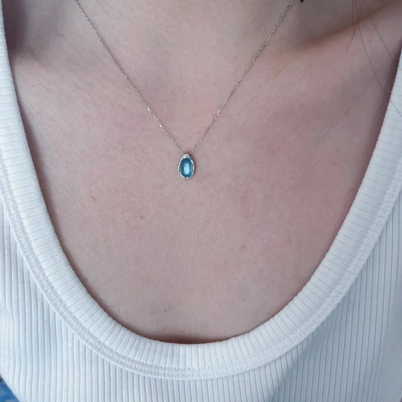 Geometric navy blue water drop pendant necklace on a model, showing the adjustable cross chain.