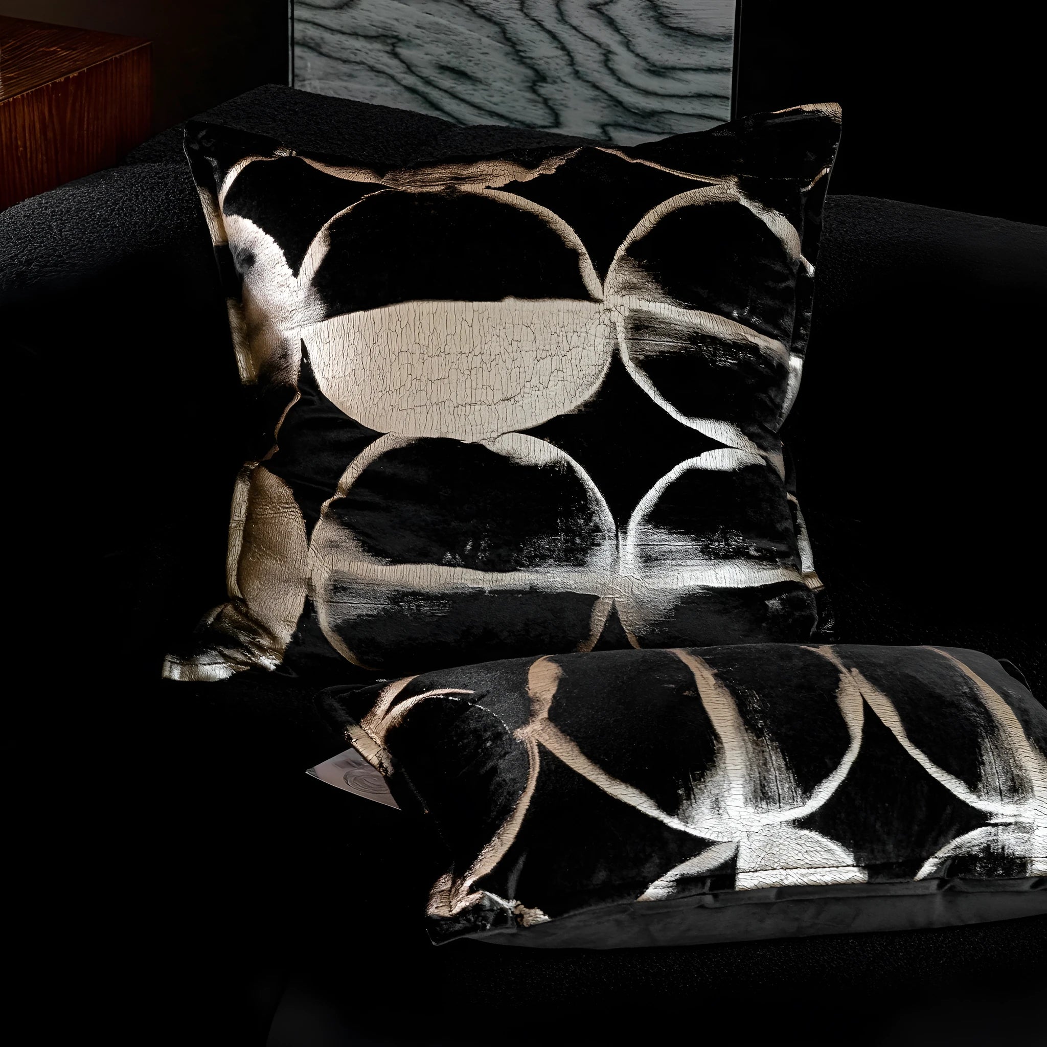 Black and gold abstract patterned flannel cushion on a sofa, showing removable cover.
