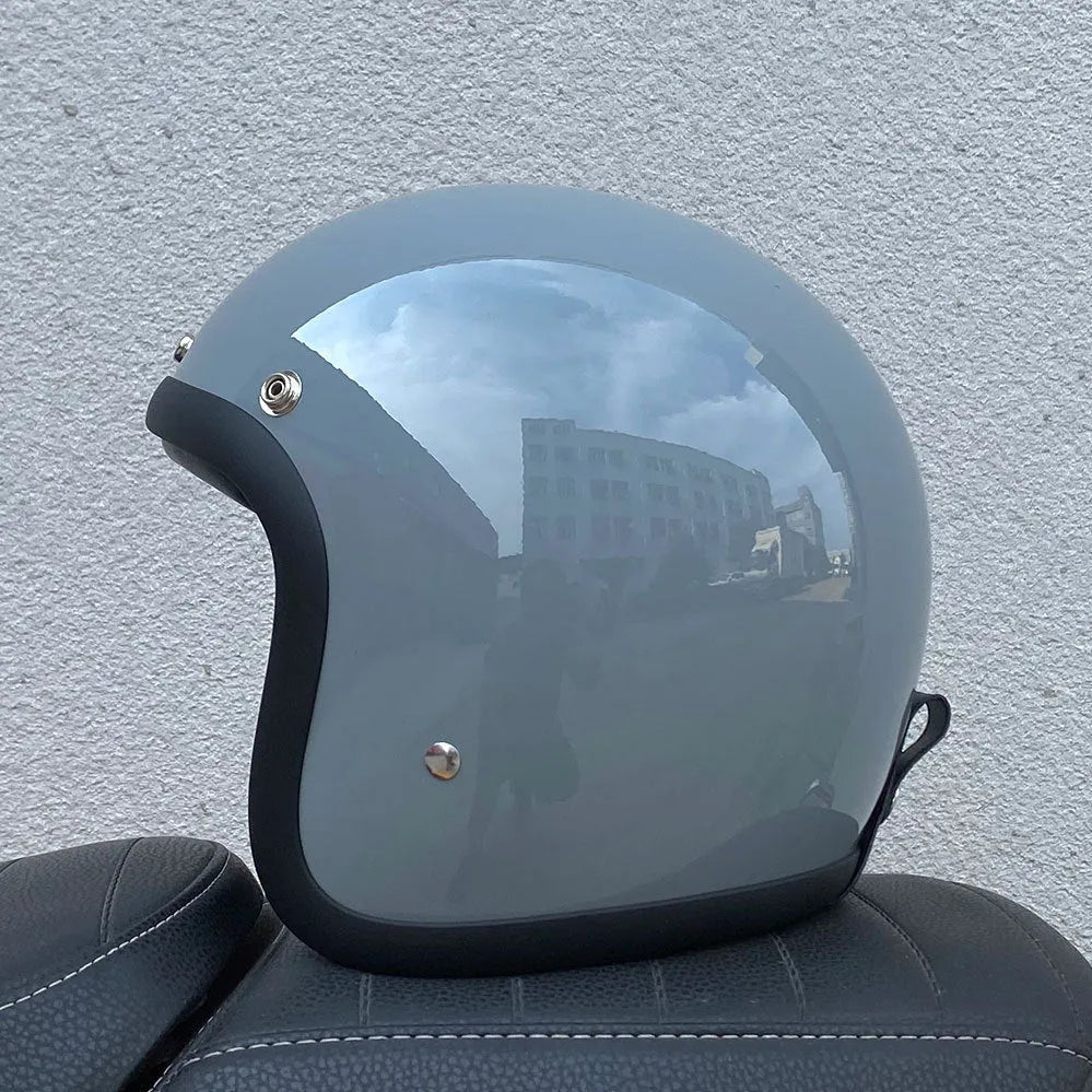 A cement grey retro-style motorcycle half helmet with a floral pattern on the side, showing its open-face design.