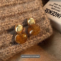 Handmade geometric earring set showing three styles: round piece, irregular amber, and water drop tigereye studs with tassels.