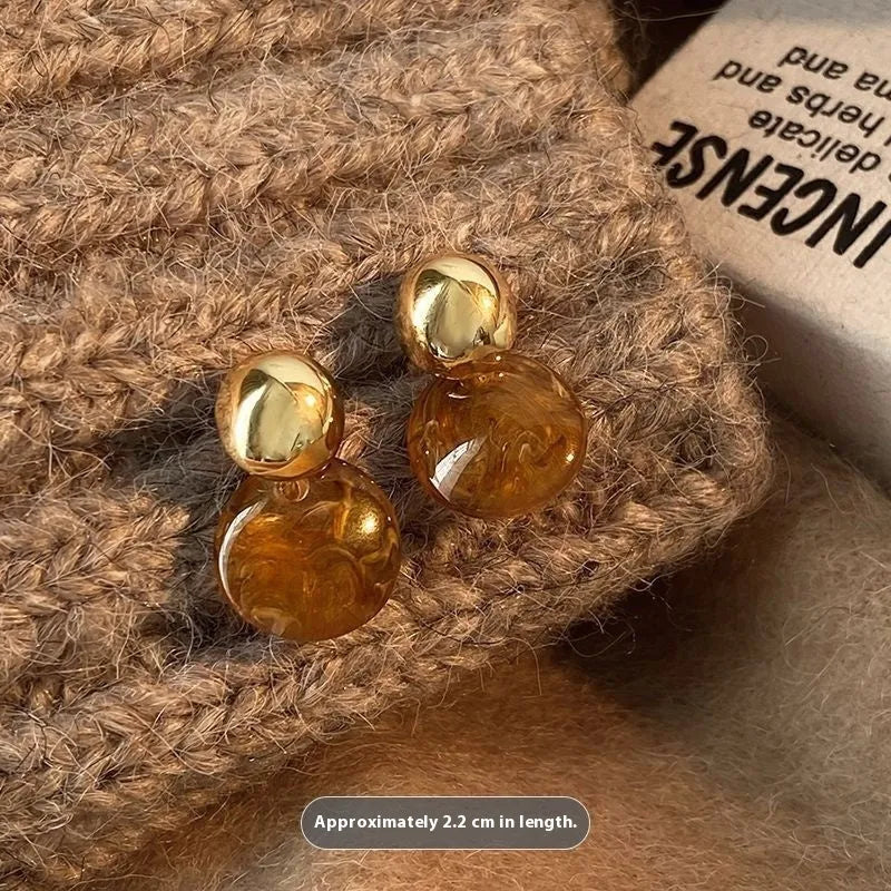Handmade geometric earring set showing three styles: round piece, irregular amber, and water drop tigereye studs with tassels.