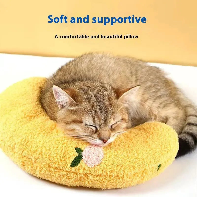 Blue U-shaped cat sleeping mat with moon design next to a yellow question mark shaped pet pillow.