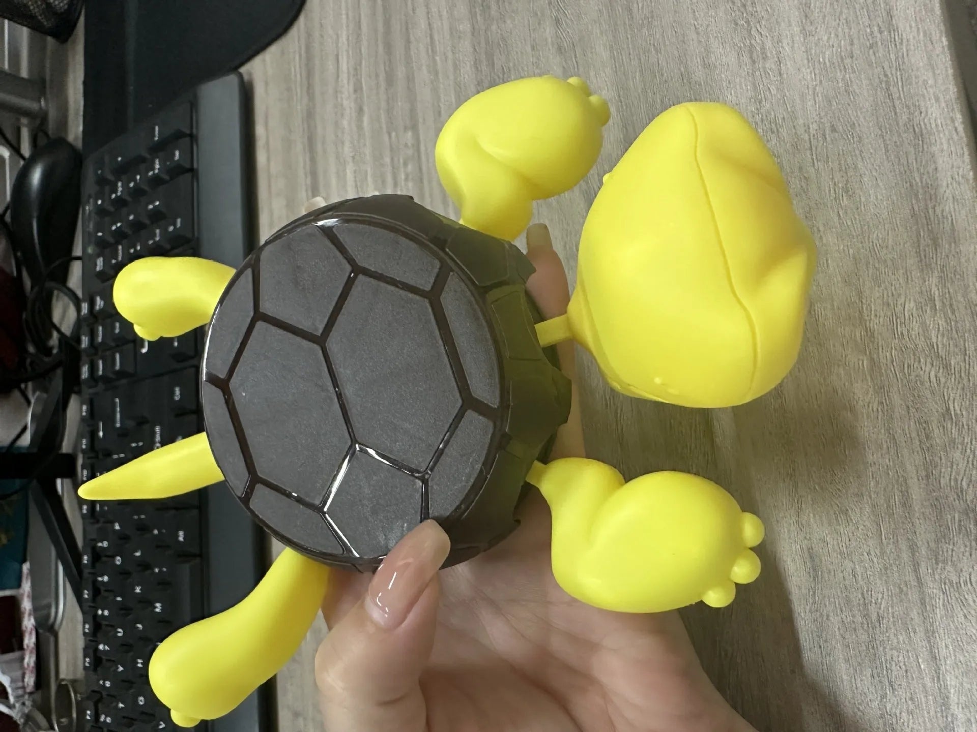 Turtle-shaped ceramic style coaster in green and yellow colours on a wooden table