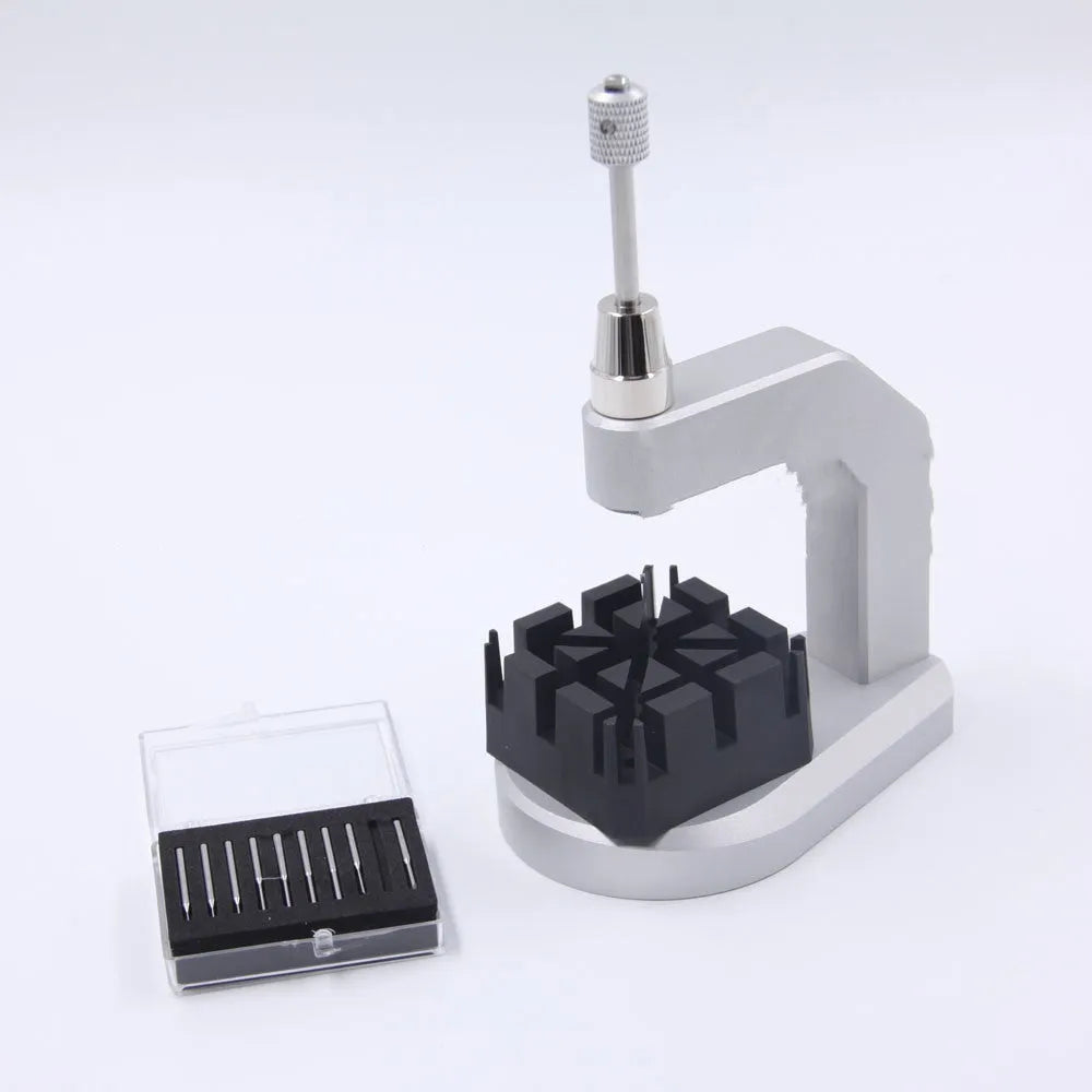 Silver coloured tool steel press strap removal tool for watch and jewellery repair on a dark surface.