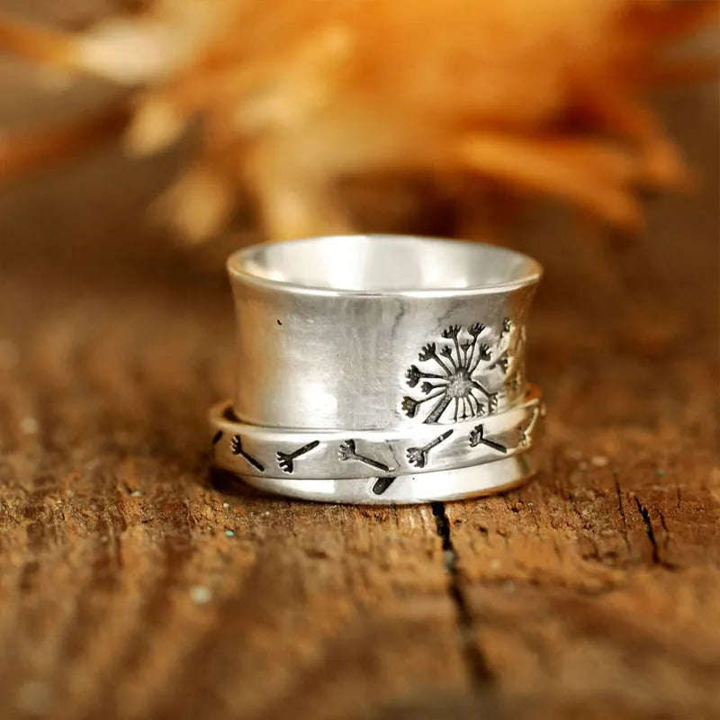 Silver electroplated alloy flower ring with rotating element on a hand.