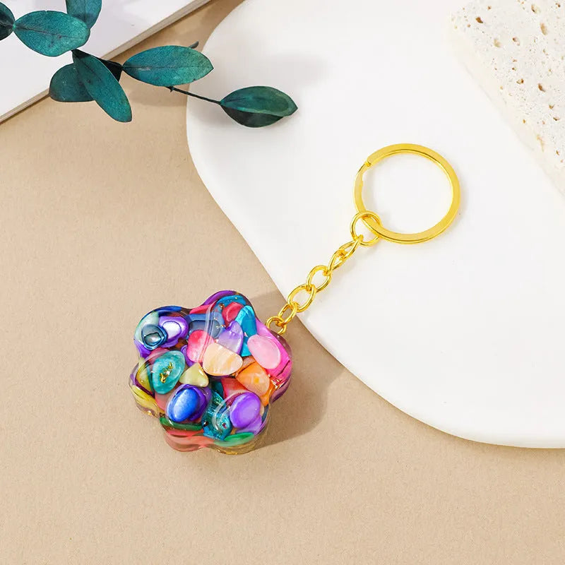 Natural crystal cat's paw shaped keychain charm on a keyring, showing colour variations of different gemstones.