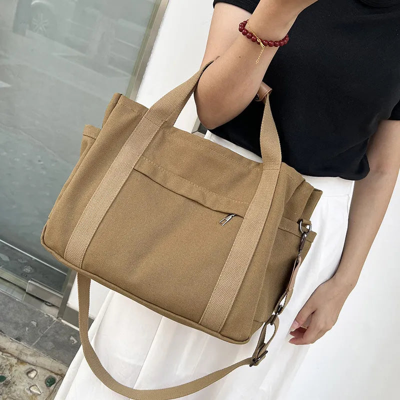 Large khaki canvas tote bag for women with open top showing internal laptop and camera pockets
