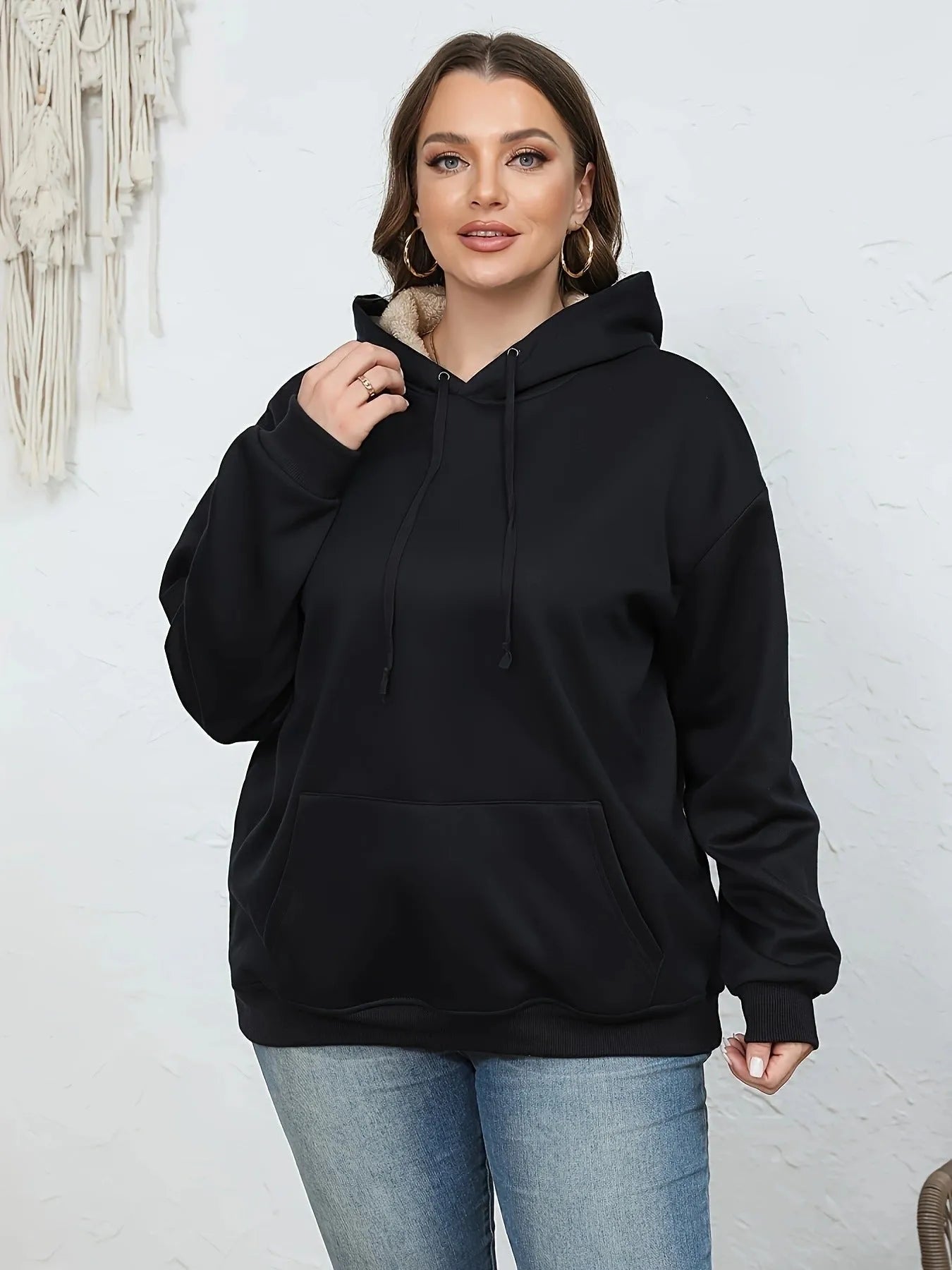 A women's loose fit hooded sweater in thick grey polyester with side pockets and long sleeves.